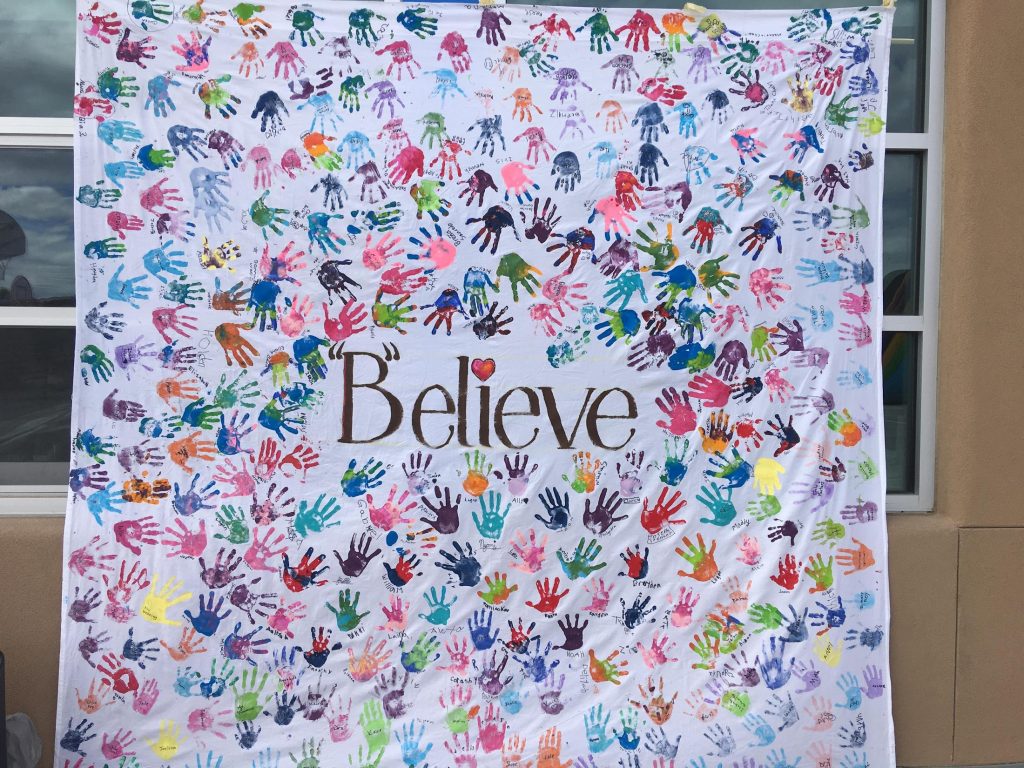 Artwork from Jefferson Elementary students with handprints surrounding the word "believe"